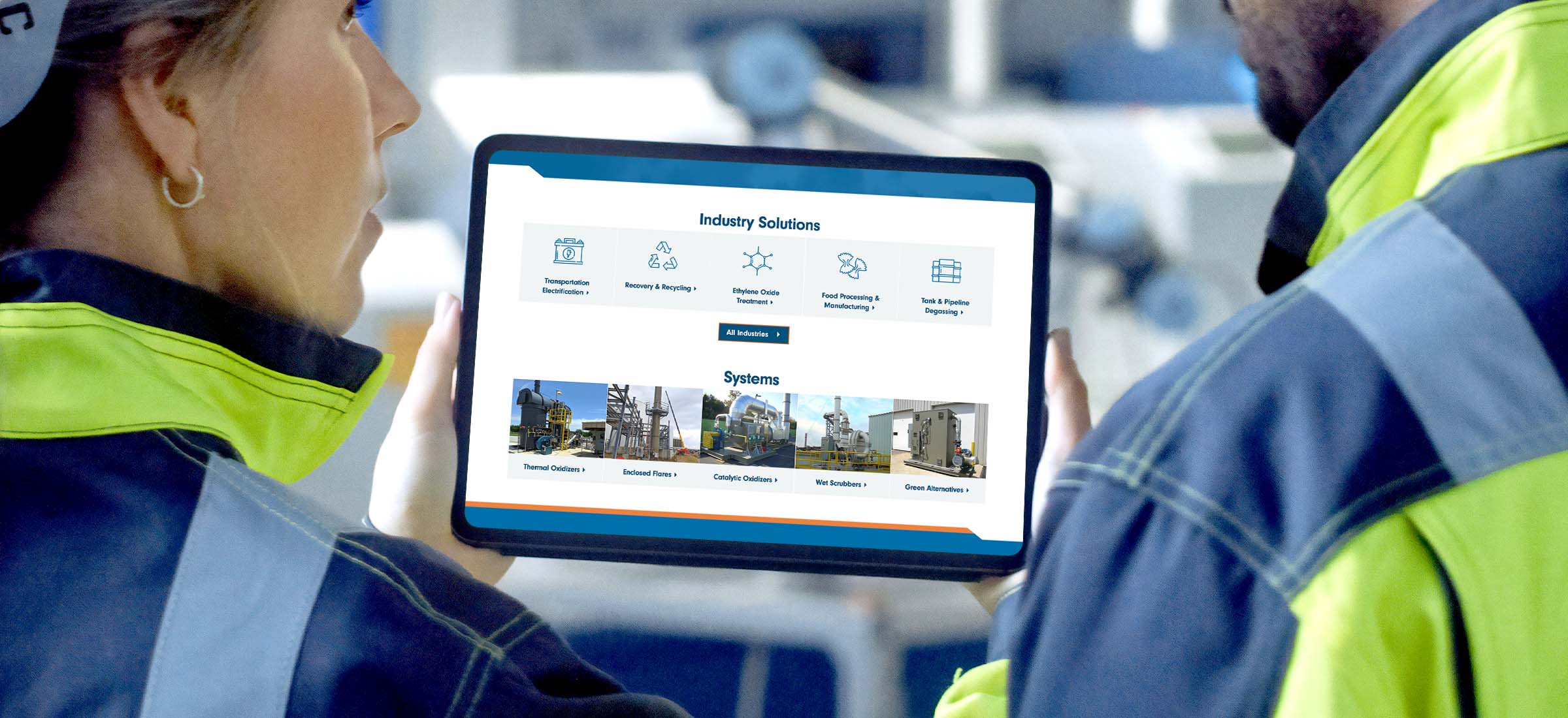Two factory workers viewing the pollution systems website on a tablet.