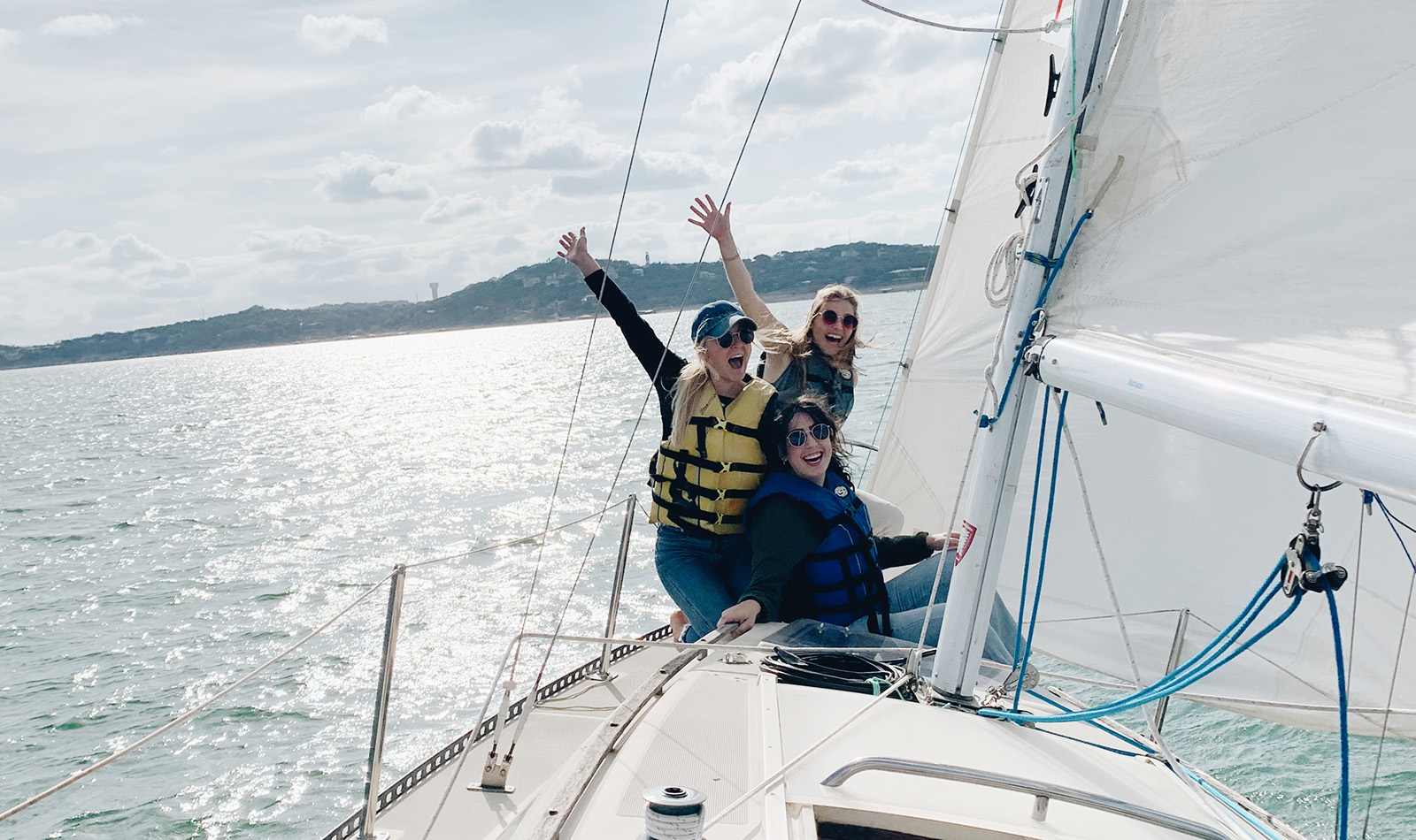 Hannah and friends on a boat waving hands in the air