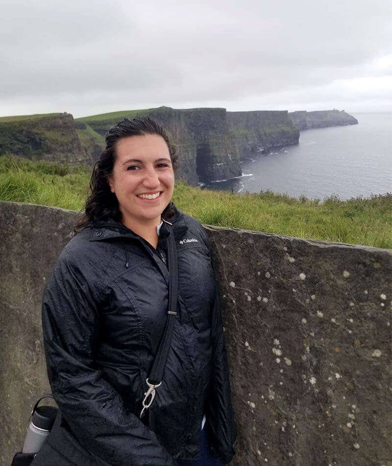 Daniela standing in front of a cliff in Ireland. 