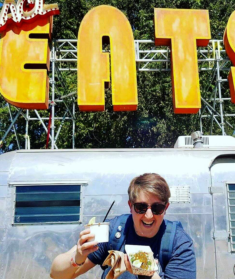 Front view of Grace holding food in front of ACL food truck.