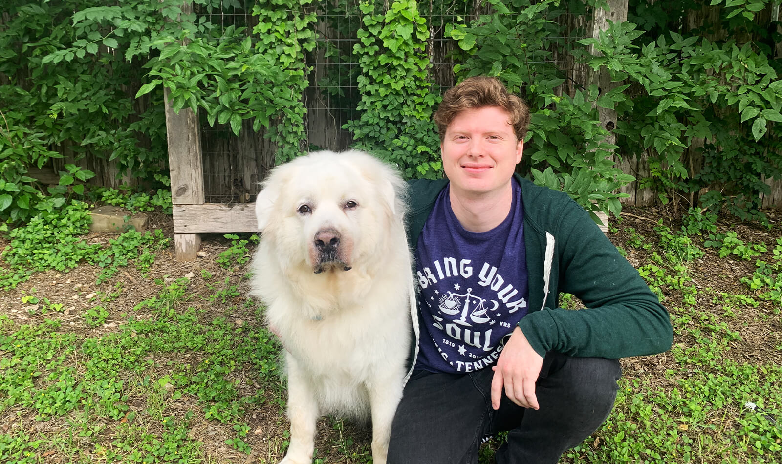 Joseph kneeling down with his Great Pyrenees.
