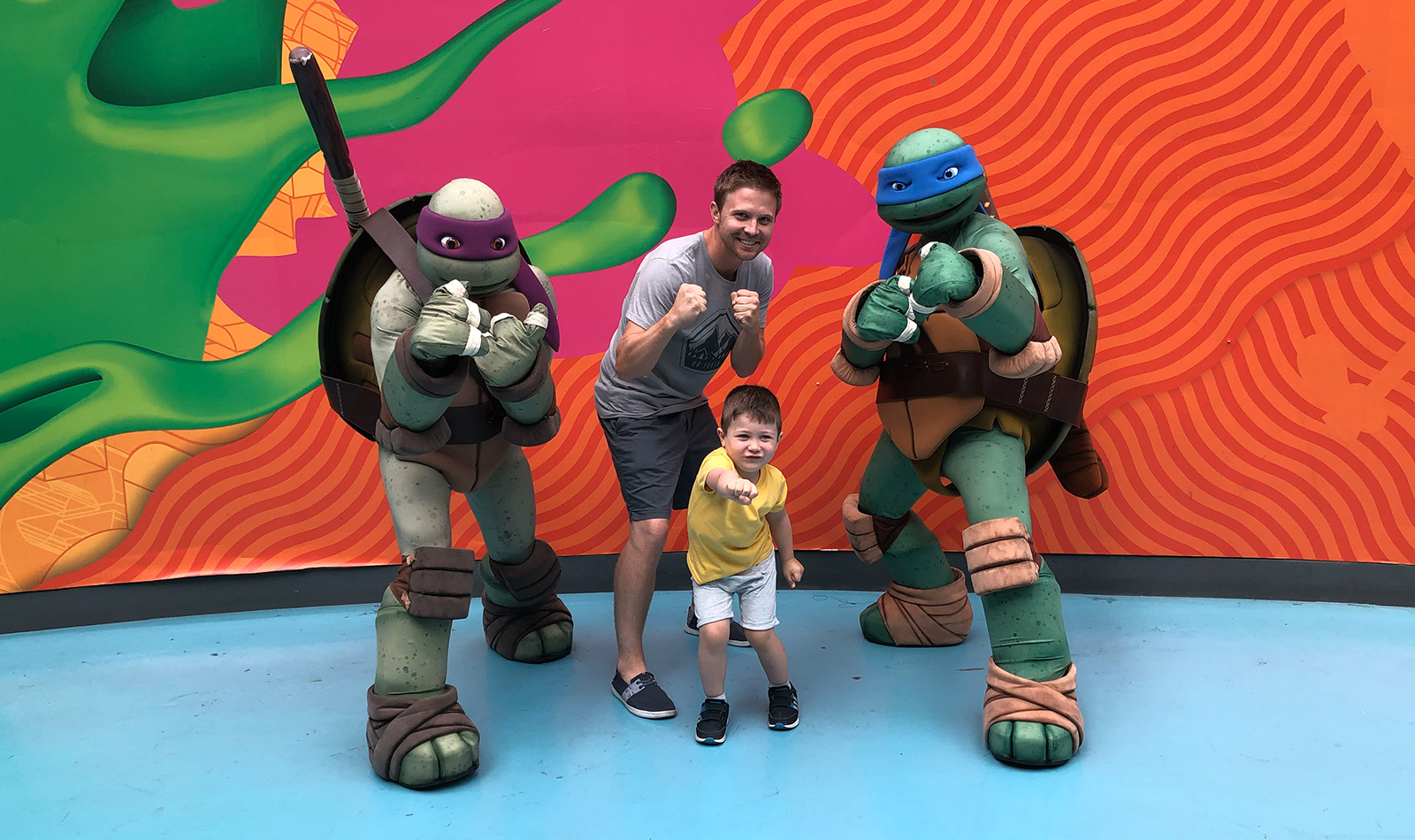 Kyle with his son standing with the ninja turtles