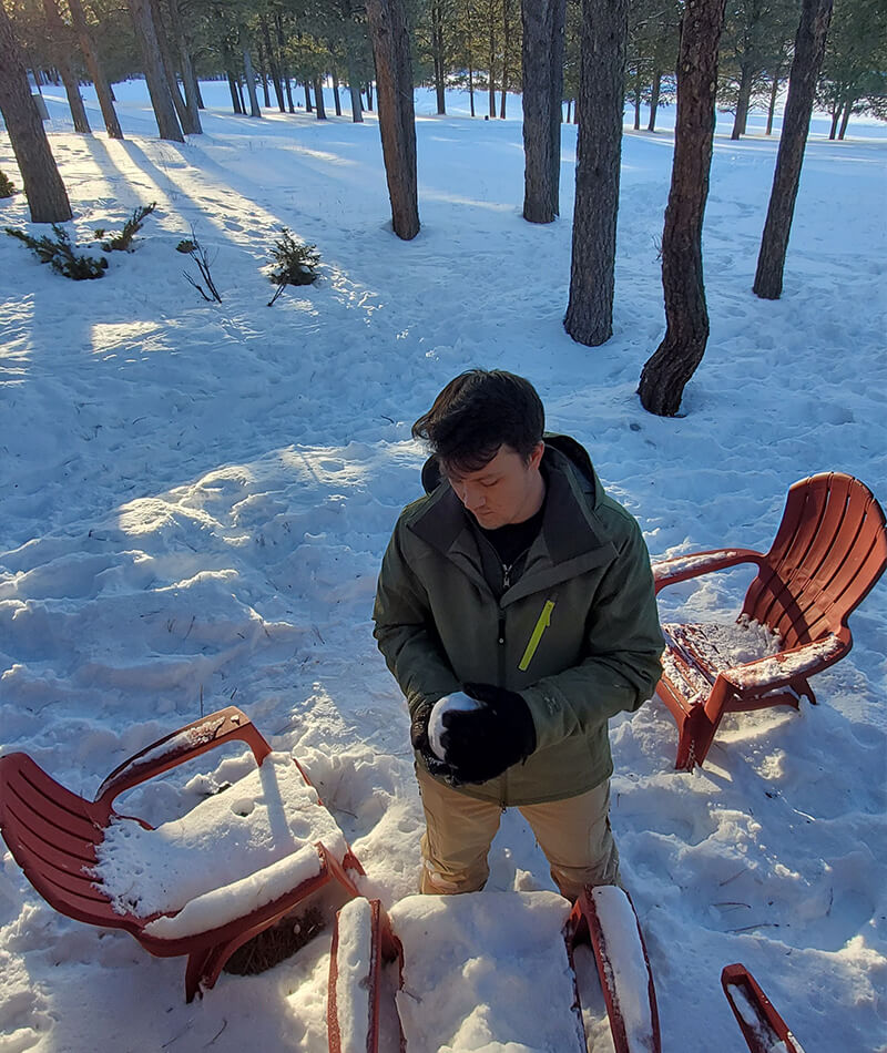 Out in a forest, knee-deep in snow, Luke prepares the perfect snowball.