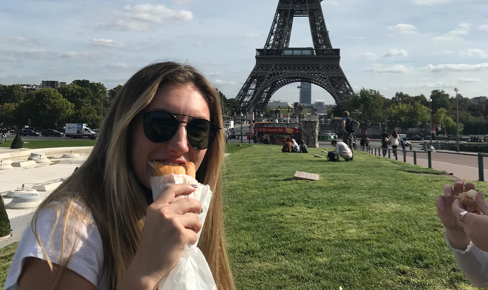 On the lawn in front of the Eiffel Tower in Paris, Ryann enjoys an authentic Parisian sandwich.