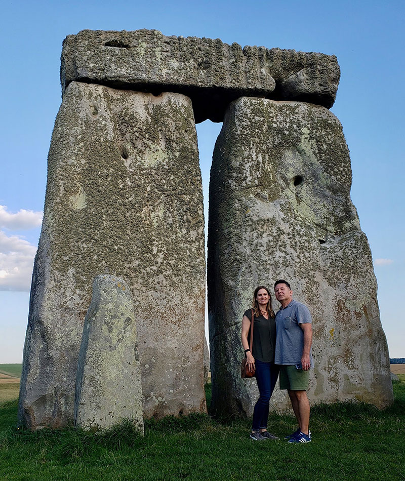 Jessica jumping mid air in-between two structures at Stonehenge in Wiltshire, England.